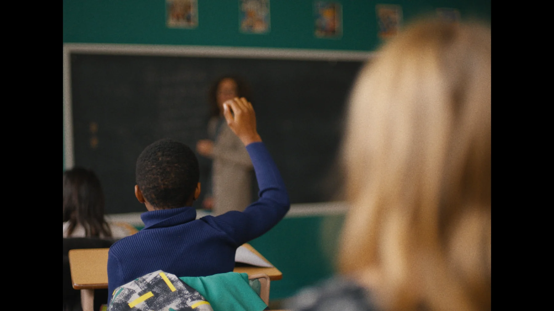 A young boy raising his hand in a classroom