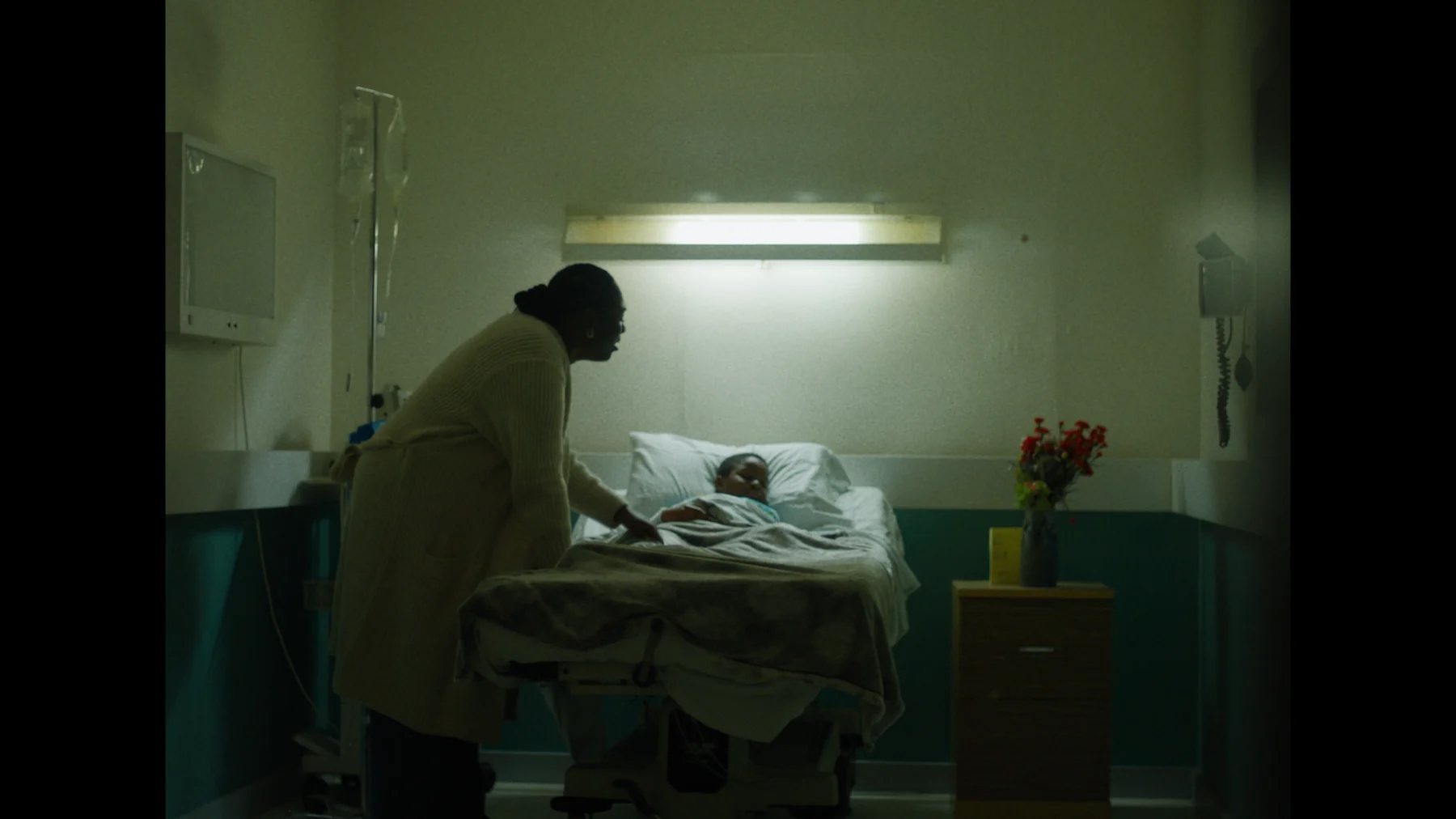 A family member beside a patient in a hospital bed