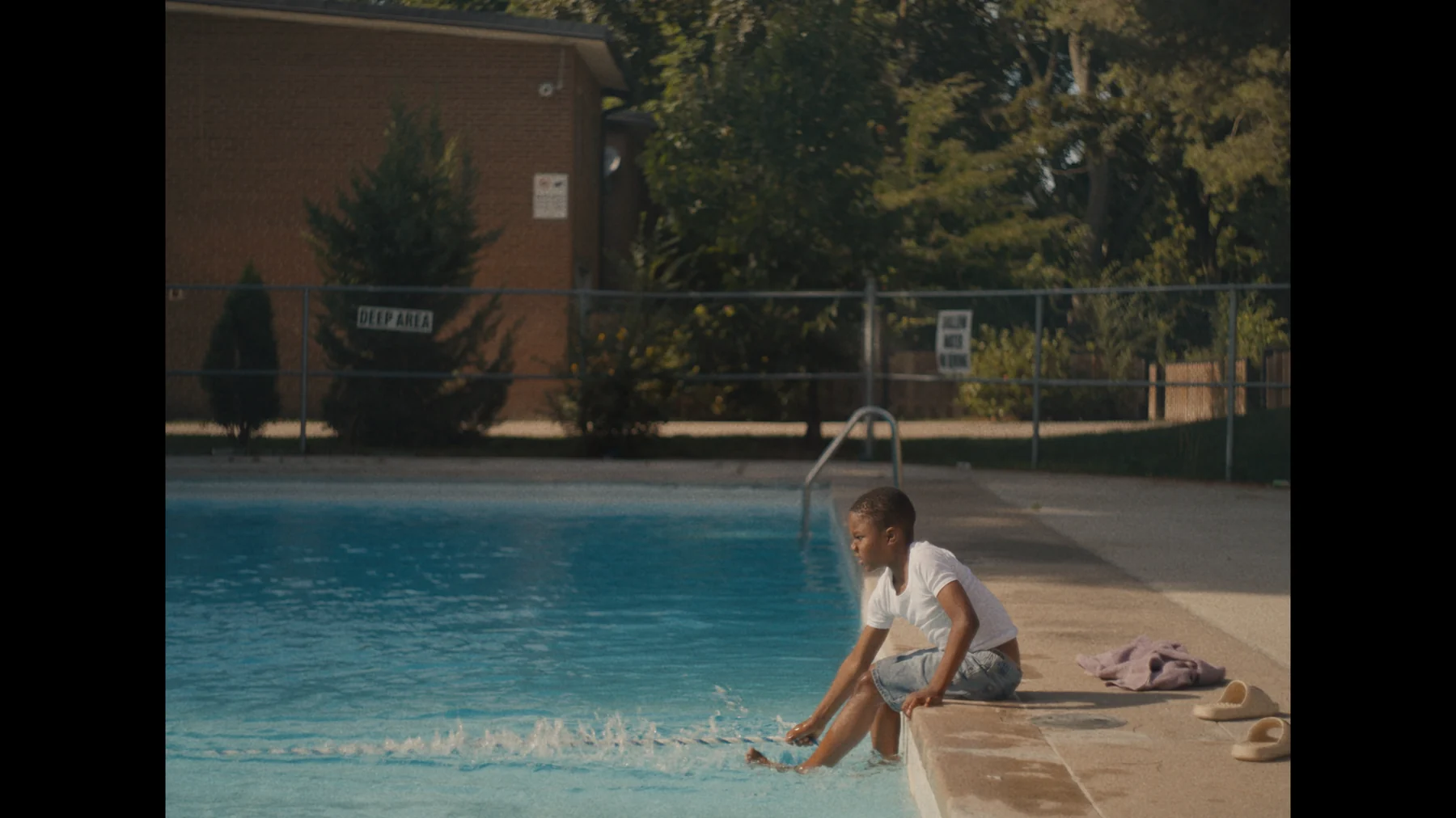 A young boy sitting at the edge of a swimming pool